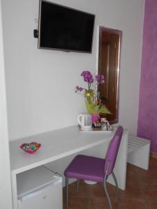 切萨雷奥港Capital Bed Porto Cesareo的白色的书桌、紫色椅子和电视