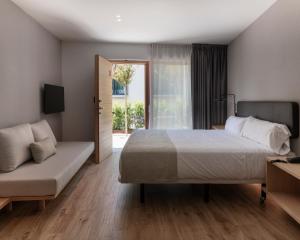 巴古尔Alta House Begur的一间卧室配有一张床、一张沙发和一个窗口