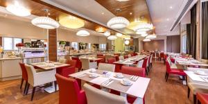 南特南特中心格兰德美居酒店的一间设有白色桌子和红色椅子的餐厅