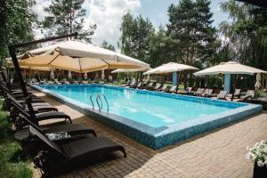 FilippovichiЗагородный отельно-ресторанный комплекс "Четыре сезона"的一个带椅子和遮阳伞的大型游泳池