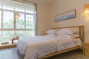 都江堰花开时民宿的一间卧室配有一张带白色床单的床和一扇窗户。
