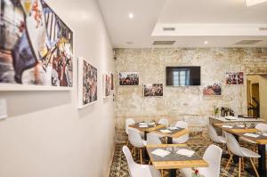 伊夫雷亚B&P La Gusteria的餐厅设有桌椅,墙上挂有图片