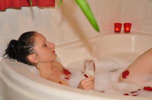 施特罗布尔格里尔公寓酒店的坐在浴缸里拿着一杯葡萄酒的女人