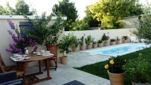 阿维尼翁L'Hibiscus Chambre d'Hôte的一个带桌子和盆栽植物的庭院和一个游泳池