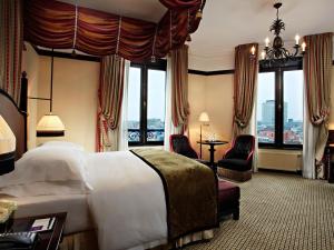 海牙Hotel Des Indes The Hague的酒店客房设有一张大床和大窗户