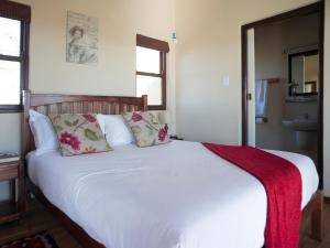 斯泰伦博斯Wild Clover Cottages的卧室配有白色的床和红色毯子