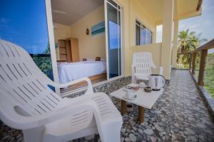 图杜马尔代夫托多轻松旅馆的一间设有两把白色椅子和一张床的房间