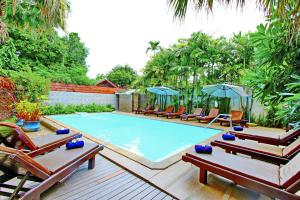 清迈瑟维瓦纳套房度假酒店的一个带椅子和遮阳伞的大型游泳池