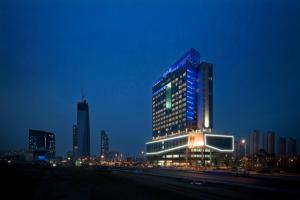 仁川市Bridge Hotel Incheon Songdo的一座高大的建筑,晚上有蓝色的灯光