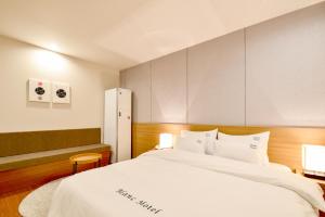 釜山布兰克商务汽车旅馆的一间卧室配有一张带白色床单的大床