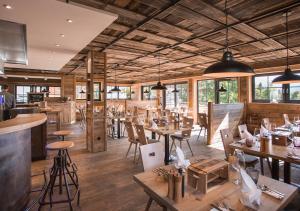 巴特欣德朗Alpin Chalets Oberjoch - Luxus Unterkunft mit privatem SPA und Zugang zu 3000 qm SPA Panoramahotel Oberjoch的餐厅设有木桌、椅子和窗户。