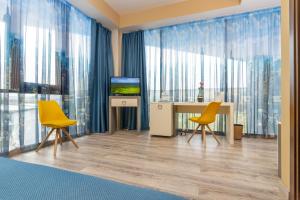 克卢日-纳波卡西城酒店的一间设有两张黄色椅子和一张桌子及电视的房间