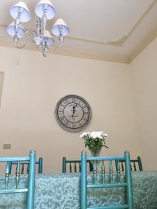 巴勒莫Casa Jolanda B&B的桌子上方的墙上挂着时钟,椅子