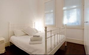珀斯Gorgeous Subiaco cottage的卧室配有白色床和毛巾