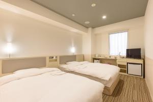 东京神田伯肯酒店的配有书桌和电视的客房内的两张床