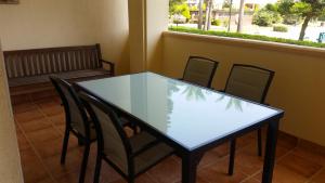 滨海罗克塔斯Apartamento Villa Romana Playa的窗户房间里玻璃桌子和椅子