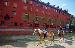 维耶拉西皮客酒店的三人在一座红色建筑前骑马