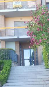 坎波马里诺appartamento Lory的一座带楼梯的建筑和一个带粉红色花卉的阳台