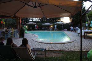 克利通诺河畔坎佩洛贝内德缇酒店的一群人坐在游泳池周围的椅子上