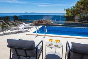 马卡尔斯卡Villa MirA with fantastic sea view的游泳池旁的天井,桌子上放着两杯玻璃