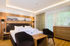 伊施格尔Hotel Garni Siegele - Silvretta Card Premium Betrieb的一间卧室配有一张大床、两把椅子和一张桌子