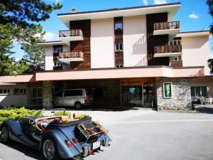 克莱恩 蒙塔纳Hotel-Restaurant Le Mont Paisible, Crans-Montana的停在大楼前的老式汽车