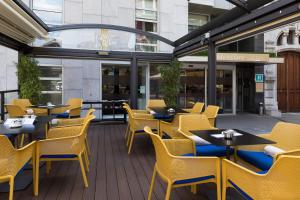 毕尔巴鄂美居加迪纳斯德艾碧亚酒店的庭院内的餐厅,配有桌椅