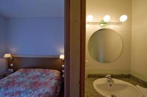 YssingeauxLogis Hotel Restaurant Le Cygne的一间带水槽和镜子的浴室以及一张床