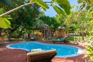 普拉兰大安塞区Villas des Alizes beachfront suites and garden villas的一个带两把椅子的游泳池以及一座房子