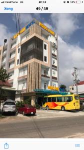 罗夷Ngọc Nam Hotel的停在大楼前的黄色巴士