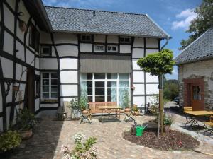 罗埃特根Ferienwohnung "im Winkelhof"的庭院内带长凳和桌子的房子