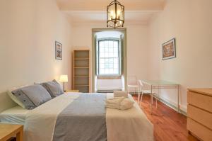 里斯本Palácio SantAnna的一间卧室配有一张床、一张书桌和一个窗户。