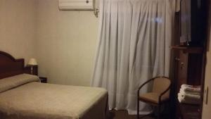 圣地亚哥-德尔埃斯特罗Hotel Libertador的卧室配有一张床和一把椅子,靠窗
