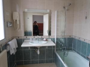 蒙特里夏尔Hôtel Le Bellevue Montrichard 3 étoiles的一位女性拍摄了一张带水槽和浴缸的浴室的照片