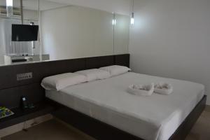 São Gonçalo do Amarante艾勒依埃拉汽车旅馆（仅限成人）的一张带两个白色枕头和镜子的白色床