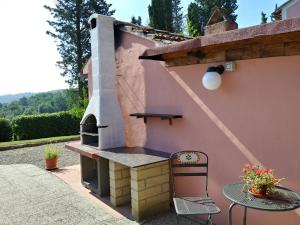 帕拉伊阿Podere Il Leccione的粉红色房子内带户外烤箱的庭院