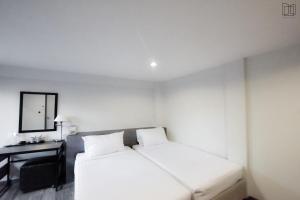 曼谷娜娜城市酒店的白色的客房配有床、书桌和镜子