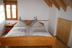 施魏根-雷希滕巴赫Gästehaus Ehrhardt的一间卧室配有一张带两个枕头的木床