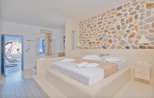 阿斯提帕莱亚镇Anatoli Luxury Studios & Suites的一间卧室设有一张大床和石墙