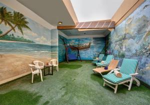 沙迦Sharjah Palace Hotel的一间设有椅子和海滩壁画的房间