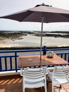 奥尔索拉Casa El Charco的海滩上一张木桌和椅子及遮阳伞