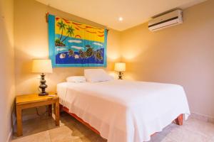 塔马林多Tamarindo Village Hotel的卧室配有白色的床和墙上的绘画作品