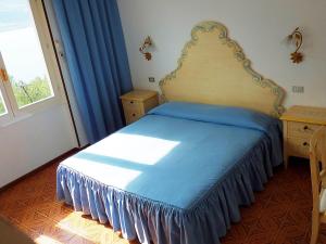 利莫内-苏尔加达玛格丽塔别墅酒店的一间卧室配有一张带蓝色床单的床和一扇窗户。