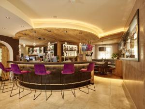 皮茨河谷圣莱昂哈德甘多夫酒店的餐厅内带紫色椅子的酒吧
