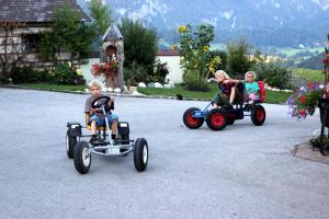 Rossleithen法米林博恩霍夫克里斯塔酒店的三个孩子在车道上骑玩具车