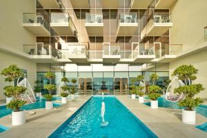 迪拜Royal Central Hotel and Resort The Palm的一座种植了盆栽植物的建筑中的游泳池