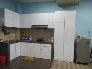 古晋齐妮亚度假屋的厨房配有白色橱柜和冰箱。