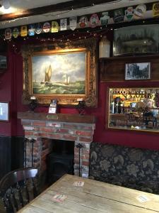 布里德波特tiger inn的餐厅内的壁炉,墙上挂有绘画作品