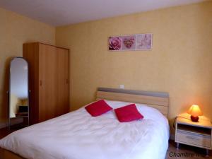Saint-Igny-de-VersAuberge Des Petits的一间卧室配有一张带两个红色枕头的床