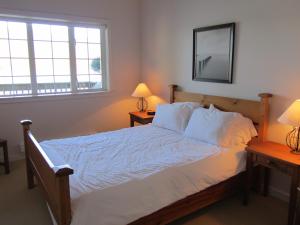 尤克卢利特水滨203公寓的一间卧室配有一张带白色床单和两盏灯的床。